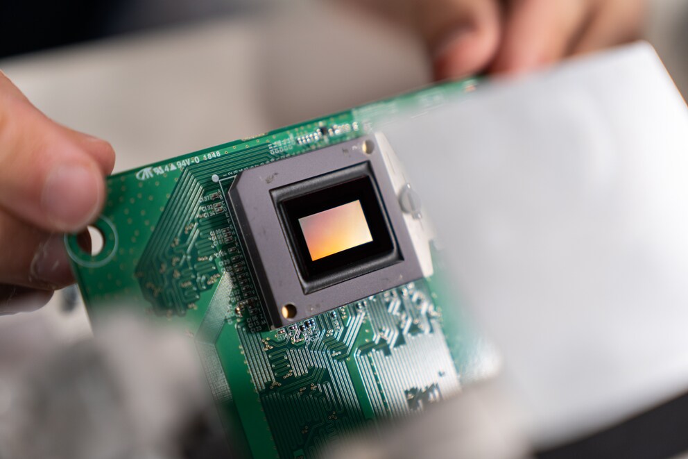 Der DMD-Chip sieht auf den ersten Blick wie ein gewöhnlicher Chip aus. Tatsächlich besteht er aus Millionen winzig kleiner Spiegel, die du von Auge nicht sehen kannst. Ähnlich wie die Pixel auf der TV-Oberfläche.
