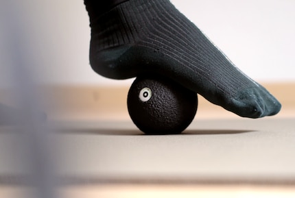 Mit einem sanften Druck wird der Fuss über dem Massageball ausgerollt.