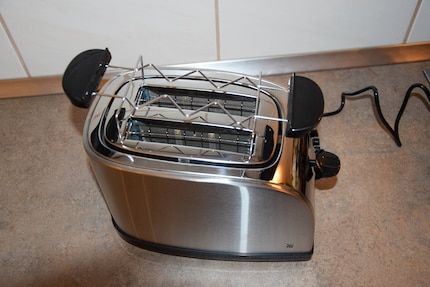 Mit im Lieferumfang dabei ist ein abnehmbarer Brötchenaufsatz. Dieser liegt bei Benutzung locker auf dem Toaster auf.