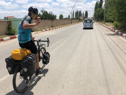 Our two cyclists ride through Döğer masked and under police escort.
