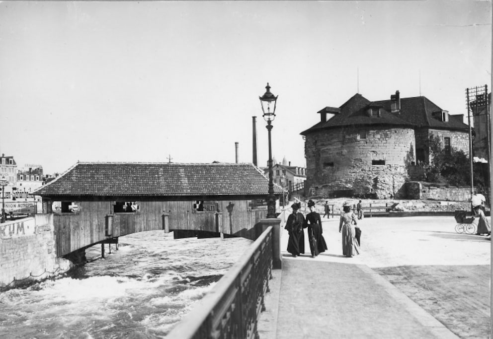 Das gedeckte Brüggli irgendwann um die vorletzte Jahrhundertwende herum, mit dem Oetenbach-Bollwerk im Hintergrund. Ganz links wird gross für Schönheit geworben.