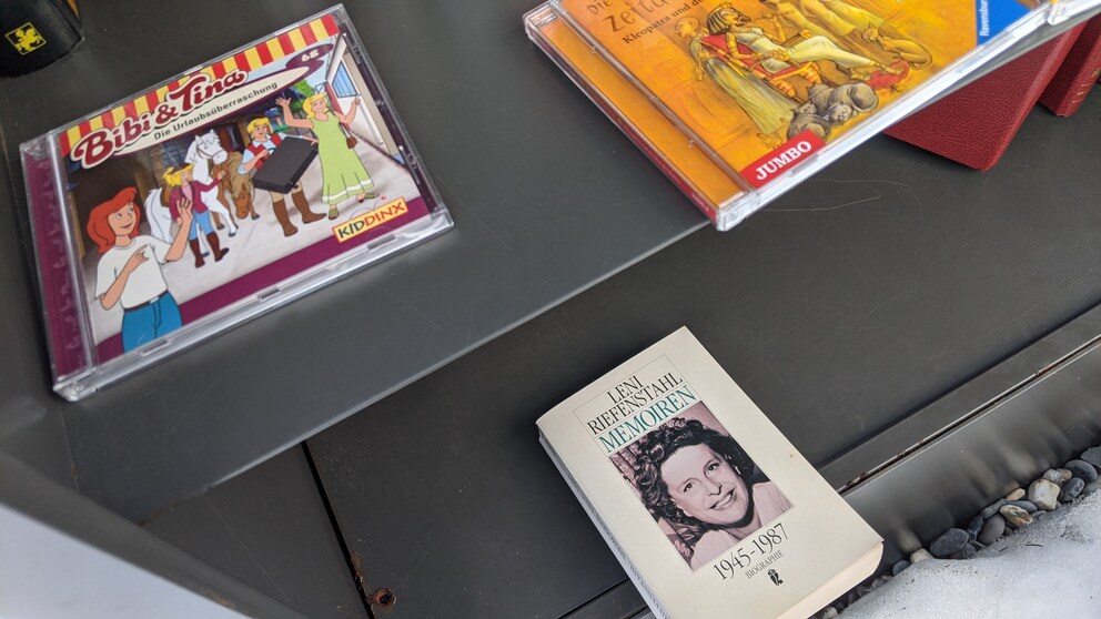 Ungleiche Nachbarinnen: Im offenen Bücherschrank prallen Welten aufeinander.