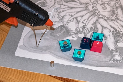 Keycaps, hot glue and small magnets are everything you need to create DIY fridge magnets.