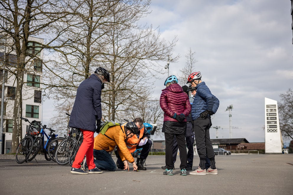 Theorie mit Kreide und einem Leuchtmarker als Velo: Kursteilnehmende diskutieren das korrekte Linksabbiegen.