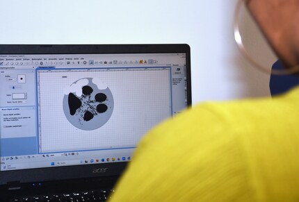 The scanned paw is edited and engraved on the pendant with a machine.