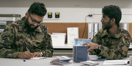 Captain Thuruban Thuchchathanan (left) filling out the pay slips with his lance corporal.