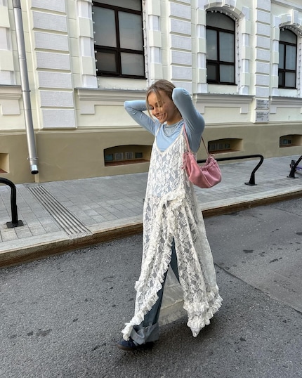 Spitzen-Maxikleid über Baggy Jeans – mehr Stilbruch geht kaum.