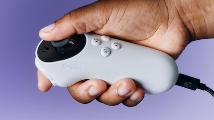The Xbox Adaptive Joystick in one hand with five fingers.