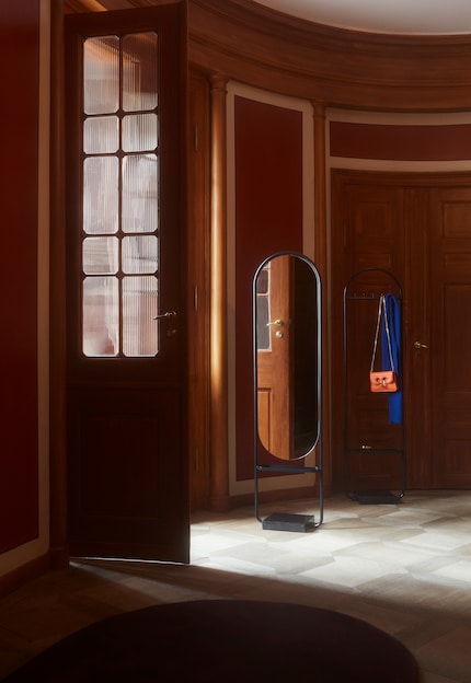 Der Spiegel reflektiert das Licht aus dem helleren Zimmer und verteilt es im dunkleren Bereich.