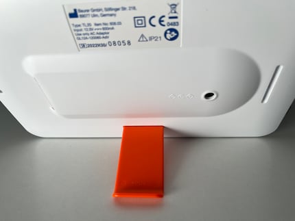Der orange Standfuß lässt sich leicht umstecken. An der Längsseite befestigt, steht die Lampe im Querformat …