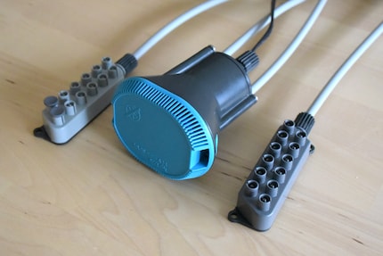 Die Pumpe (Mitte) ist mit Distributor 1 (links) und Distributor 2 (rechts) über Schläuche und Gewinde verbunden. Die dritte Pumpenöffnung (mittiger Deckel zwischen grauen Schläuchen) ist verschlossen.