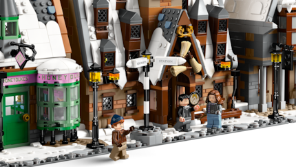 Harry, Hermione and Ron sit in front of the Hog's Head in the middle of snowy Hogsmeade.